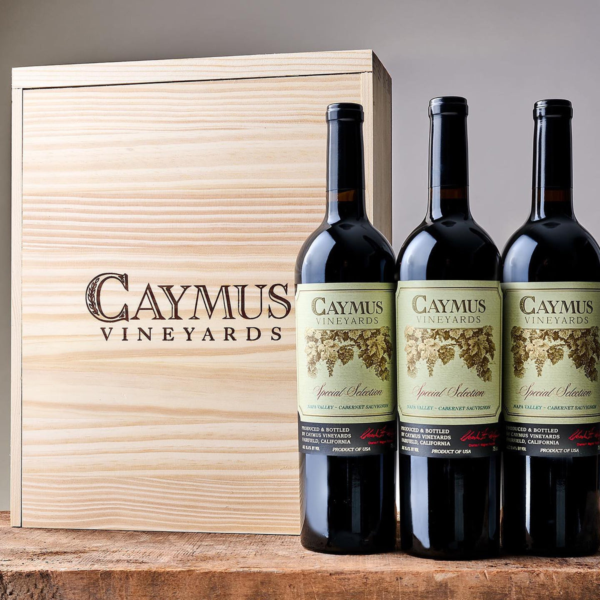 Three bottles of Caymus Special Selection Cabernet Sauvignon beside a Caymus Vineyards wooden case